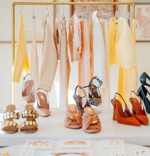 Rack of pastel spring clothing above a display of heeled sandals