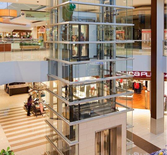 Glass elevator shaft rising through a multi-level mall atrium