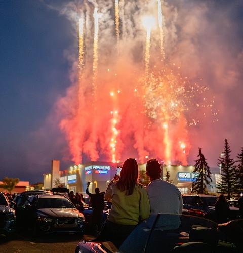 Couple watching fireworks over the mall at night from the parking lot