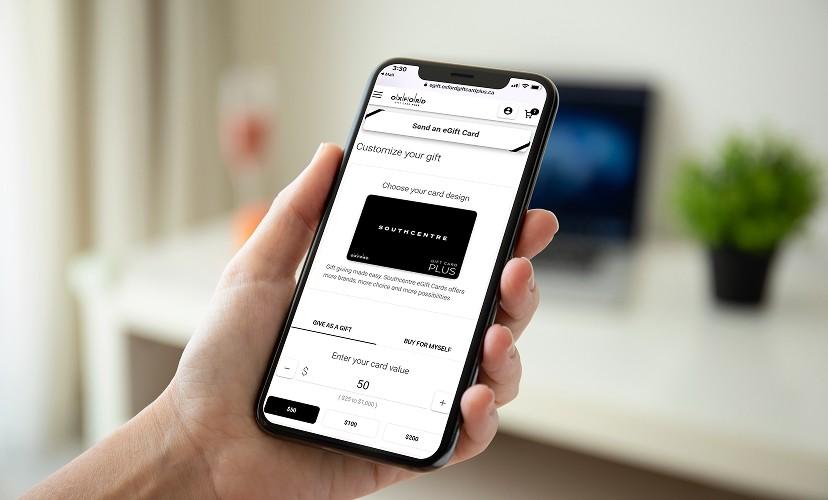 Hand holding a phone showing the Southcentre eGift card design and value options