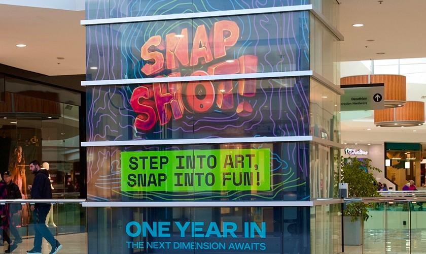 Colourful Snap Shop art activation display on a mall glass elevator column