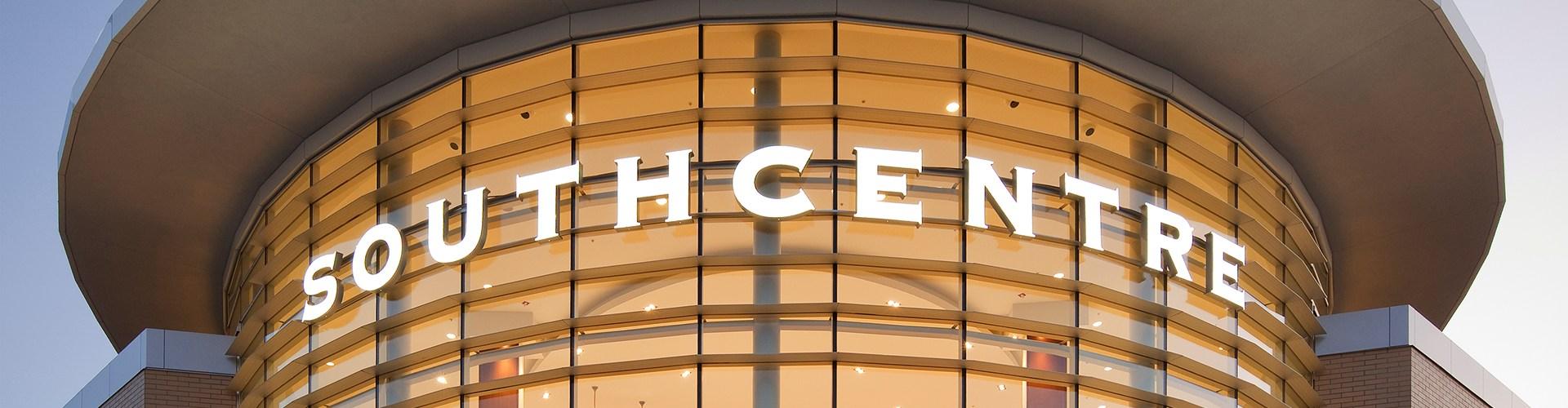 Illuminated curved Southcentre sign on the mall's glass facade at dusk