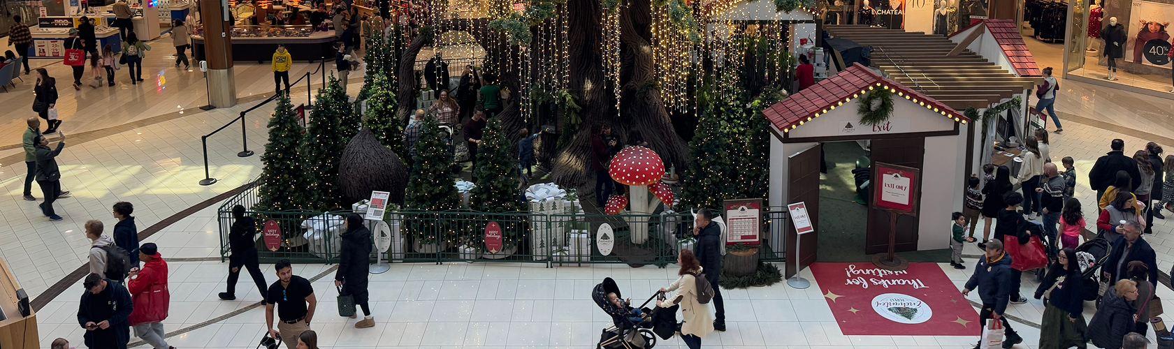 Busy mall interior with a decorated Christmas tree and holiday market huts