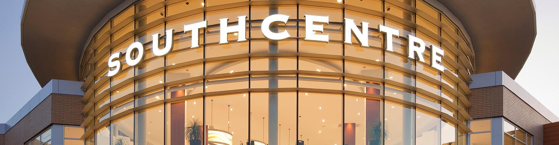 Illuminated curved Southcentre sign glowing gold on the glass facade at dusk