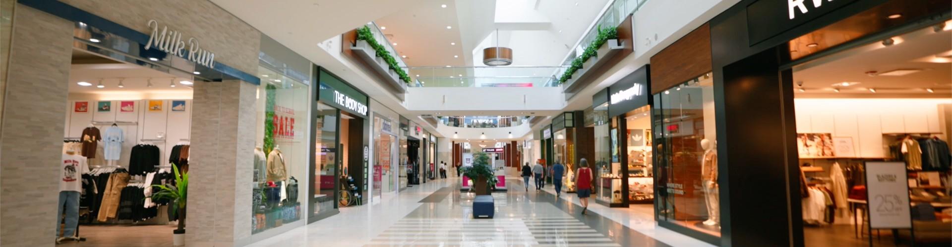 Mall walkway lined with Milk Run and The Body Shop under a skylight