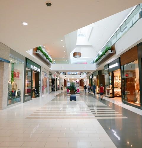 Mall walkway lined with Milk Run and The Body Shop under a skylight