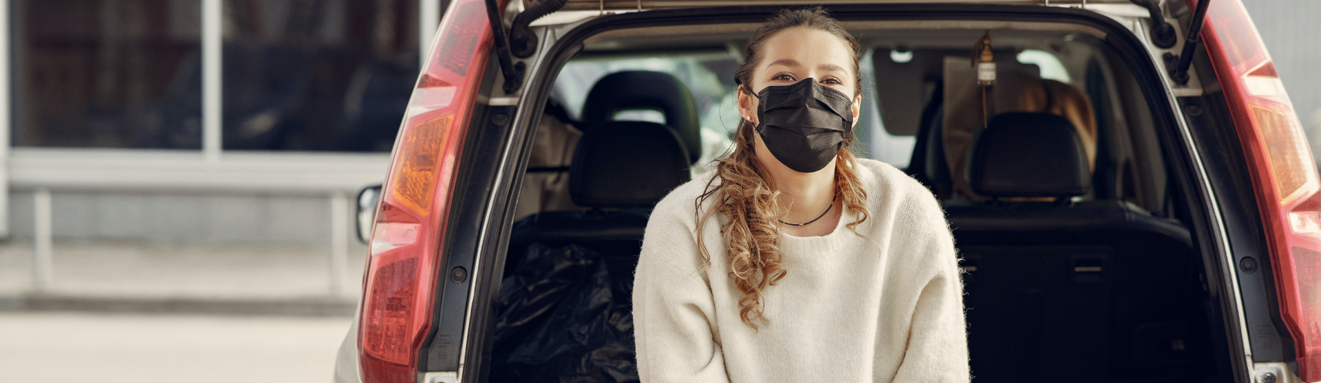 Girl with a face mask behind a car