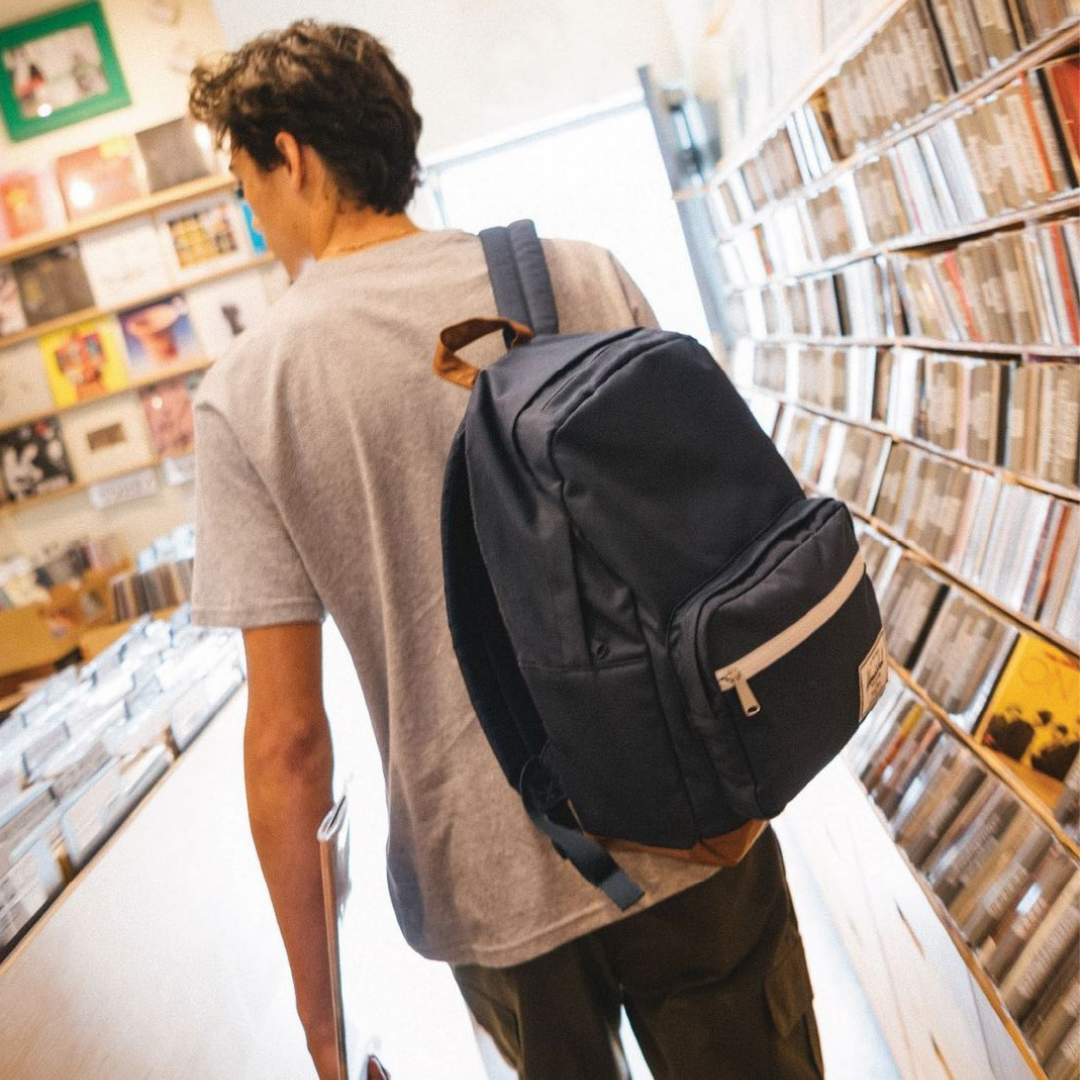 Guy walking through record store with navy backpack