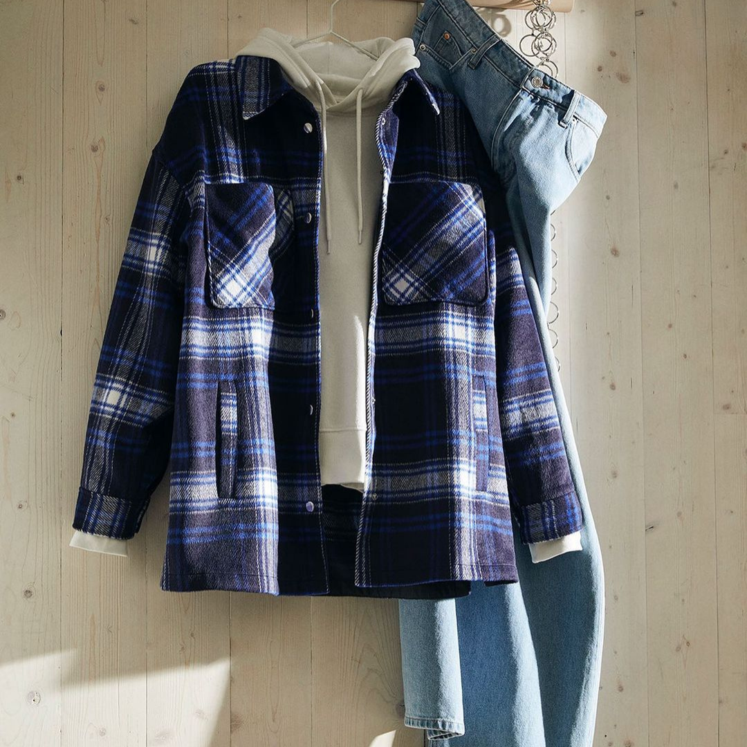 Flannel top layered with a white hoodie underneath and light coloured jeans