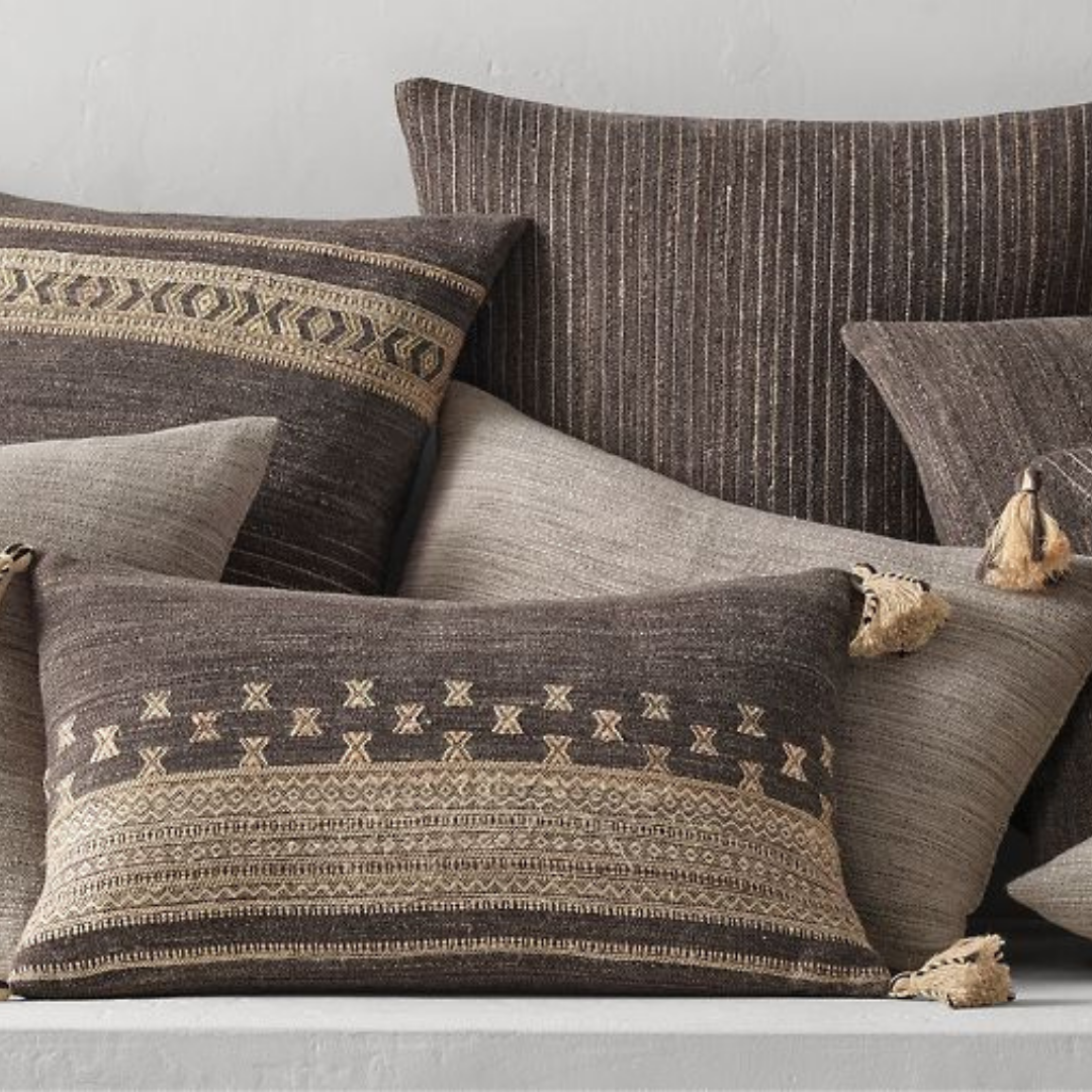 A pile of grey and beige pillows with different prints