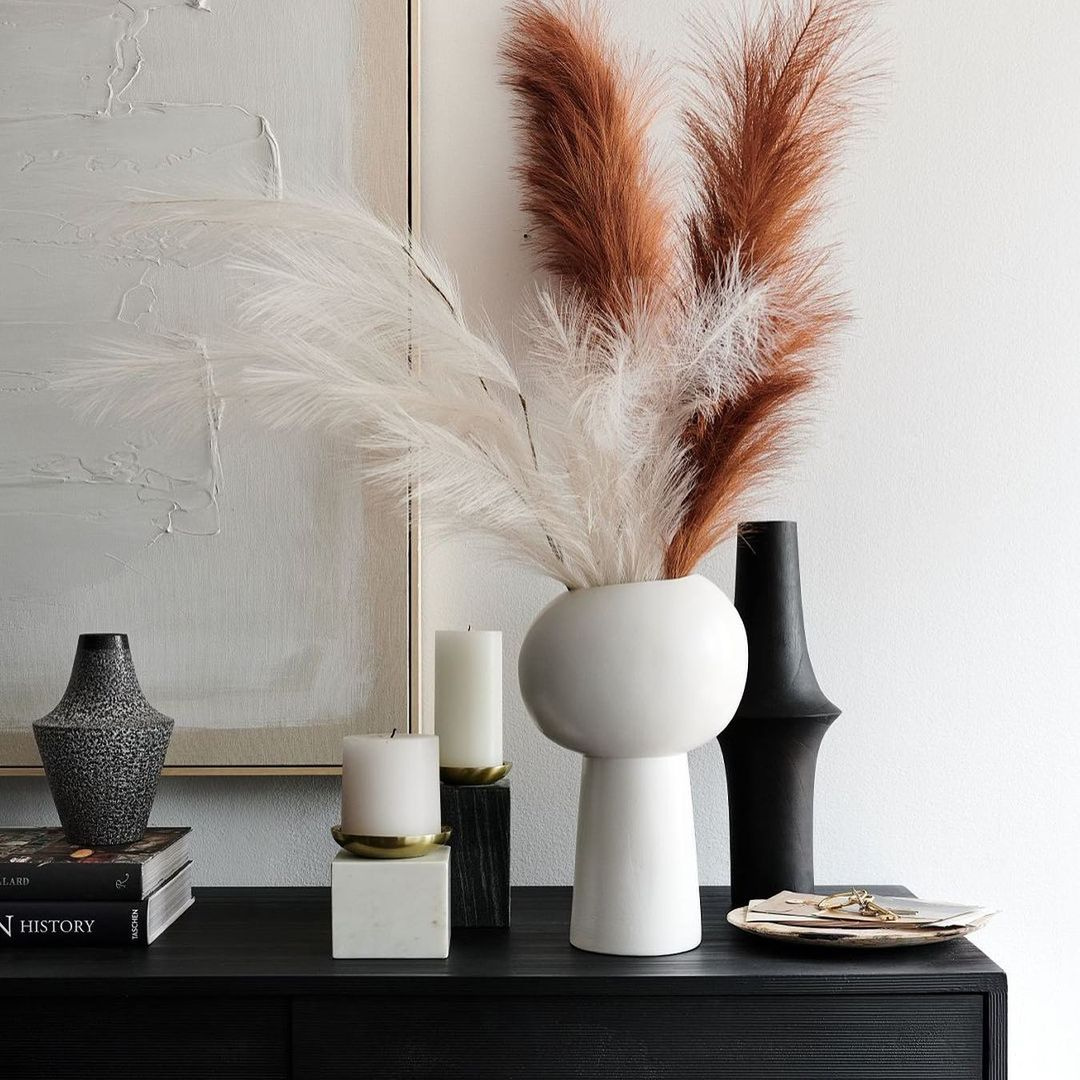 Dried flowers in a white vase on a black table