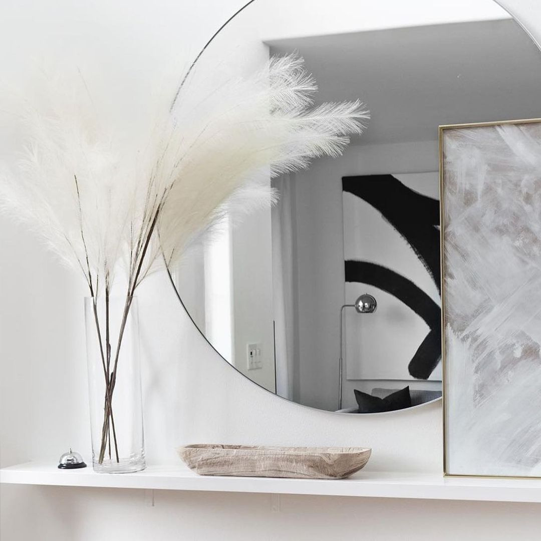 Dried flowers in a glass vase with a large round mirror