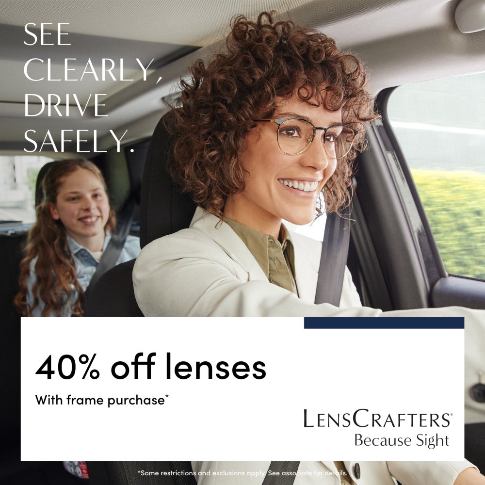 Woman smiling and driving with child sitting in back seat
