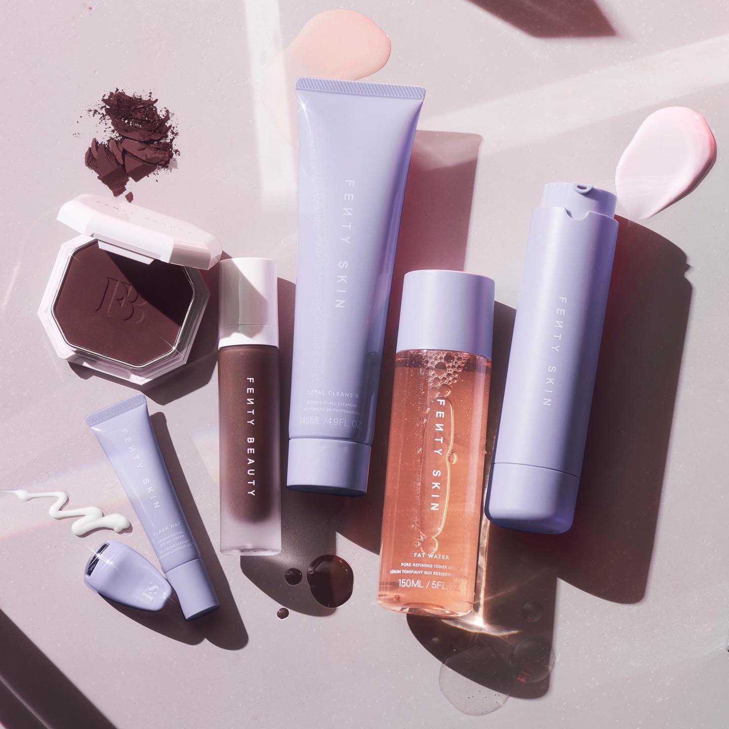 Various Fenty Beauty and Fenty Skin products are laid out on a light background.