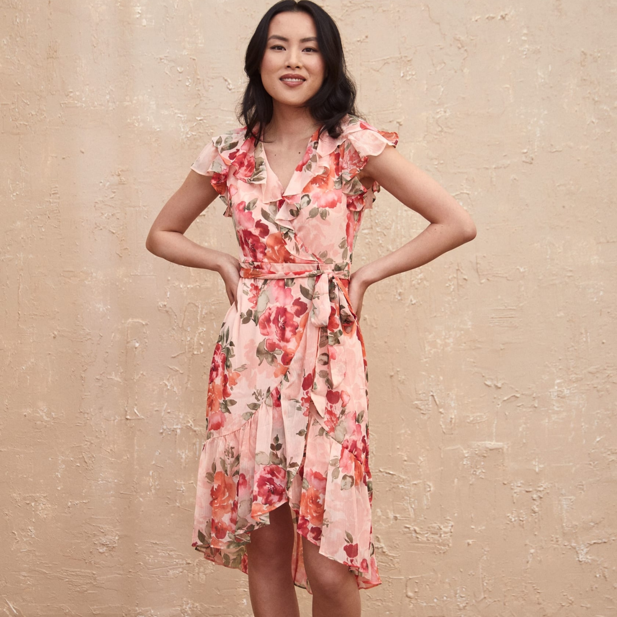 A dark haired woman models a floral pink dress from Laura.