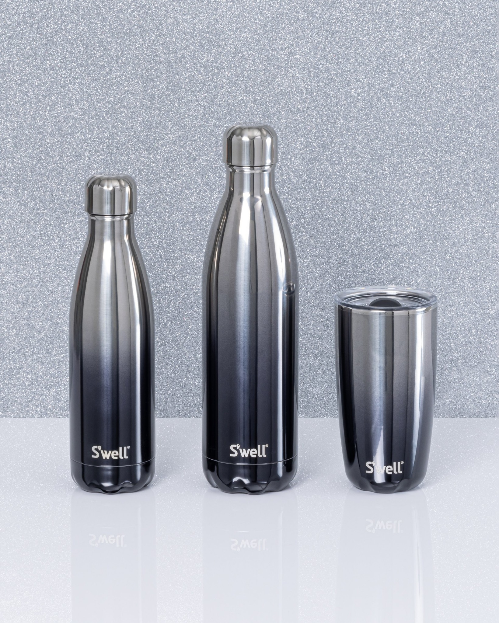 Three different sized S'well water bottles are all the same black to silver ombre design.