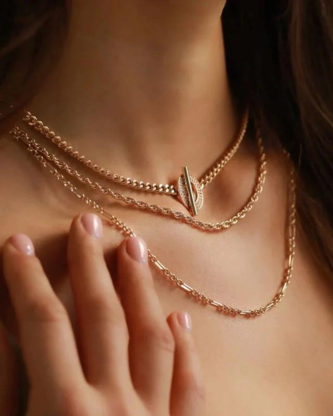 An up close view of a person wearing layered gold necklaces from Joydrop.