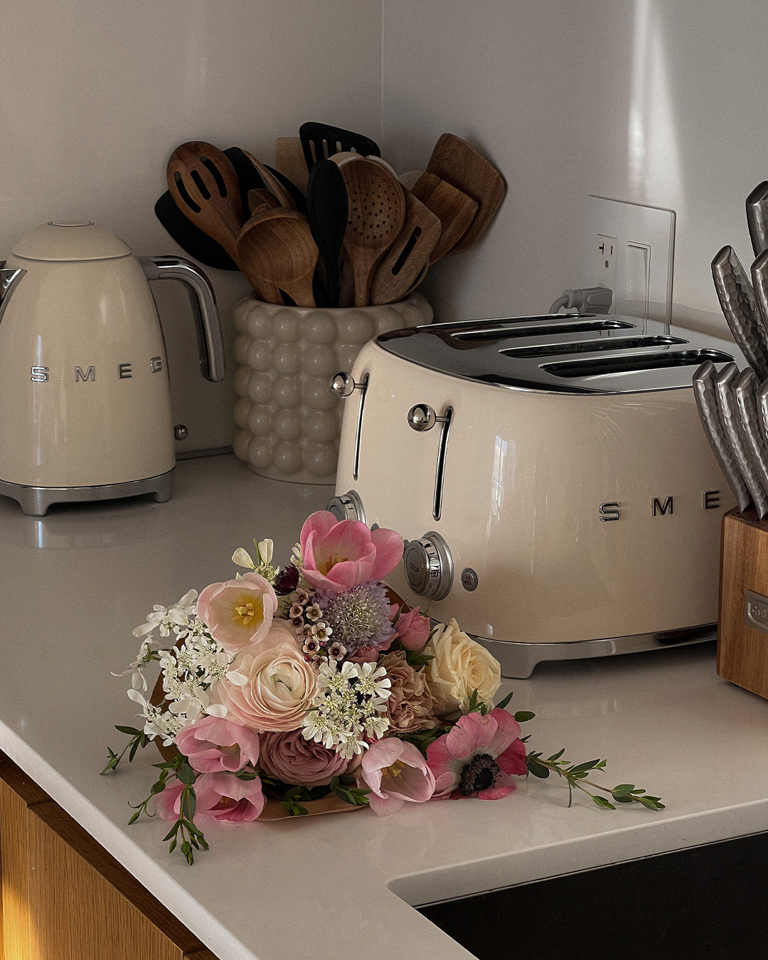 Smeg kitchen appliances sit on a counter top alongside flowers.