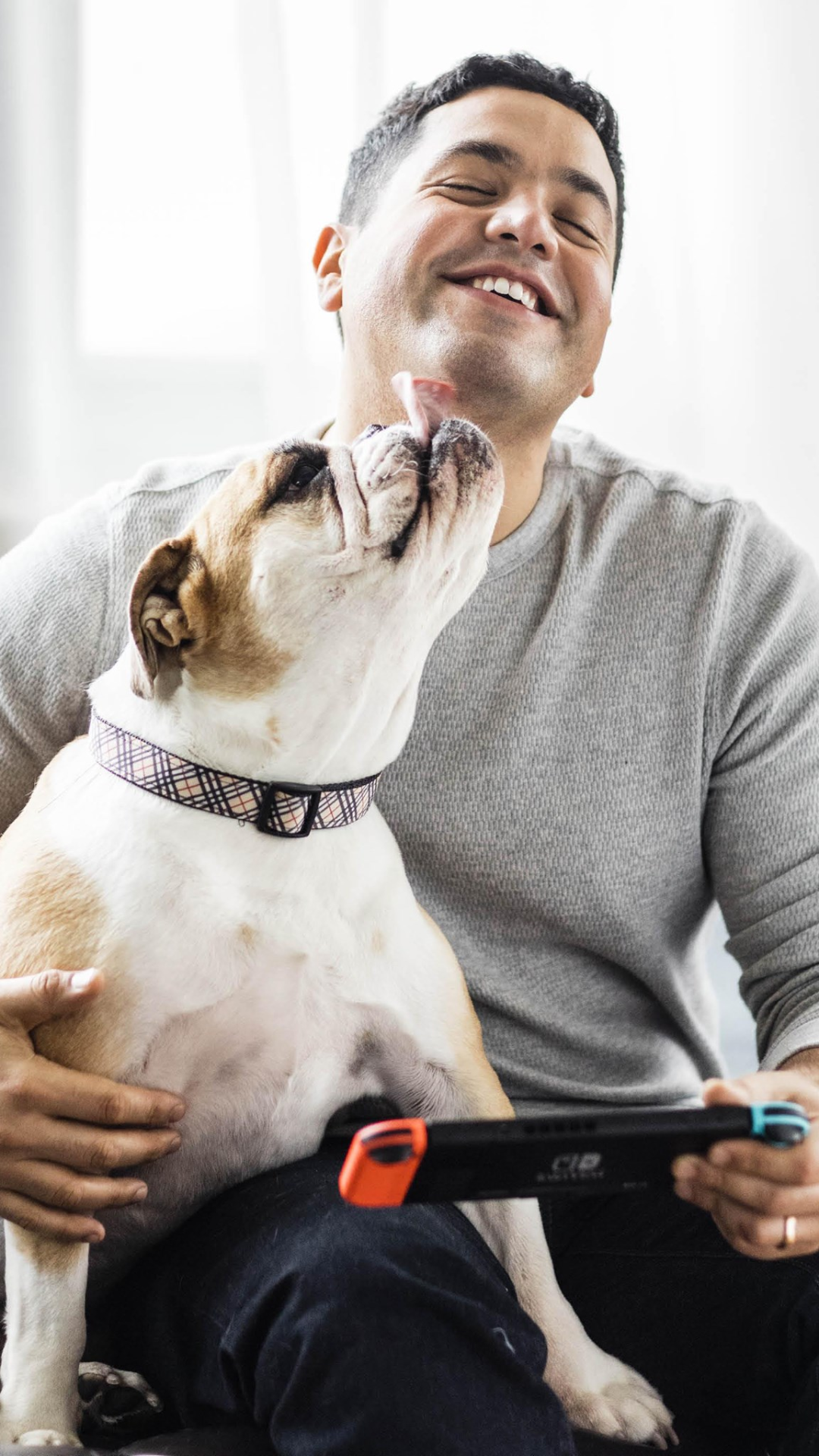 image of man with a dog in his lap. the man is holding a game controller