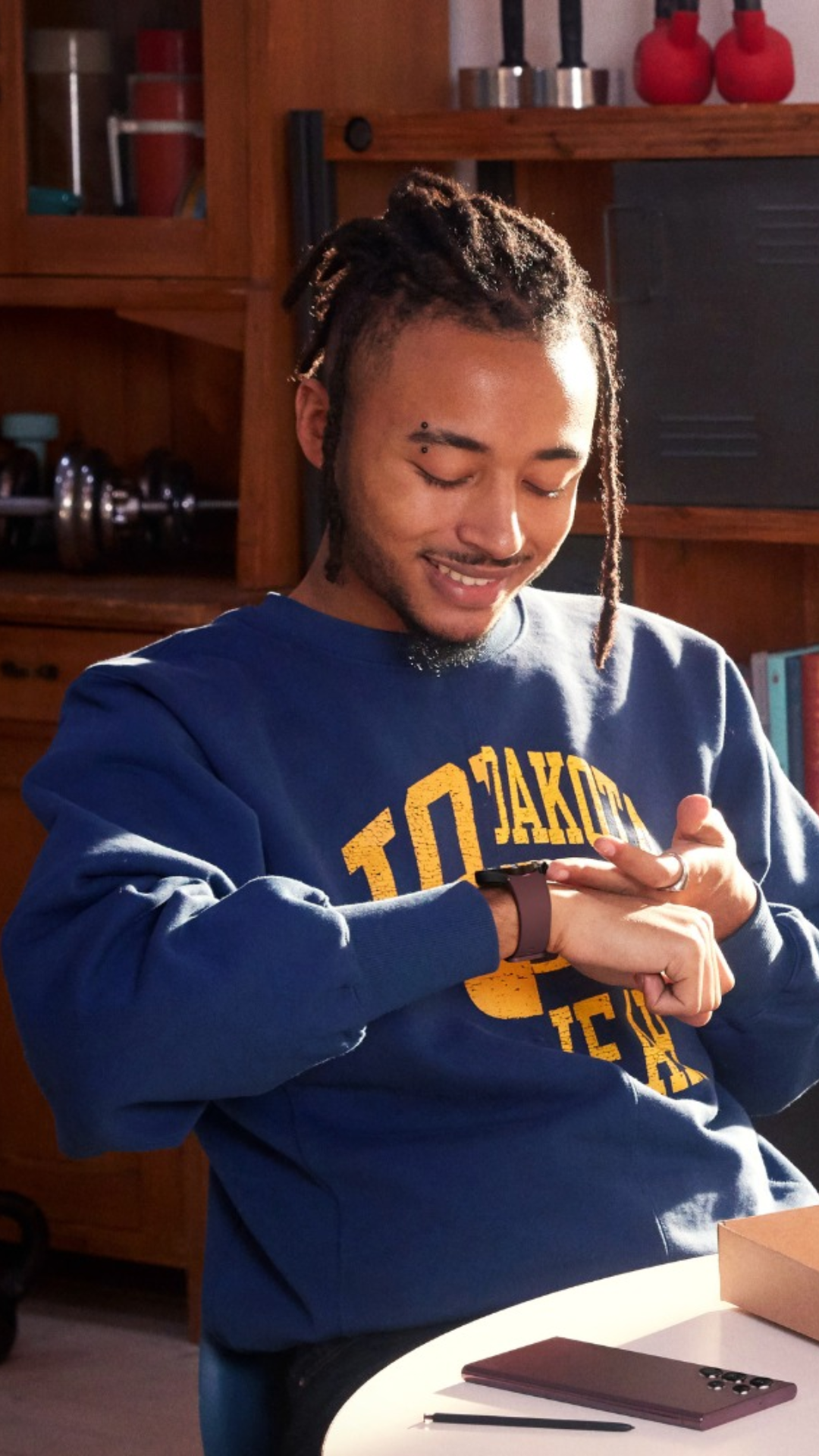 image of a man wearing a blue crewneck sweater looking at a smartwatch