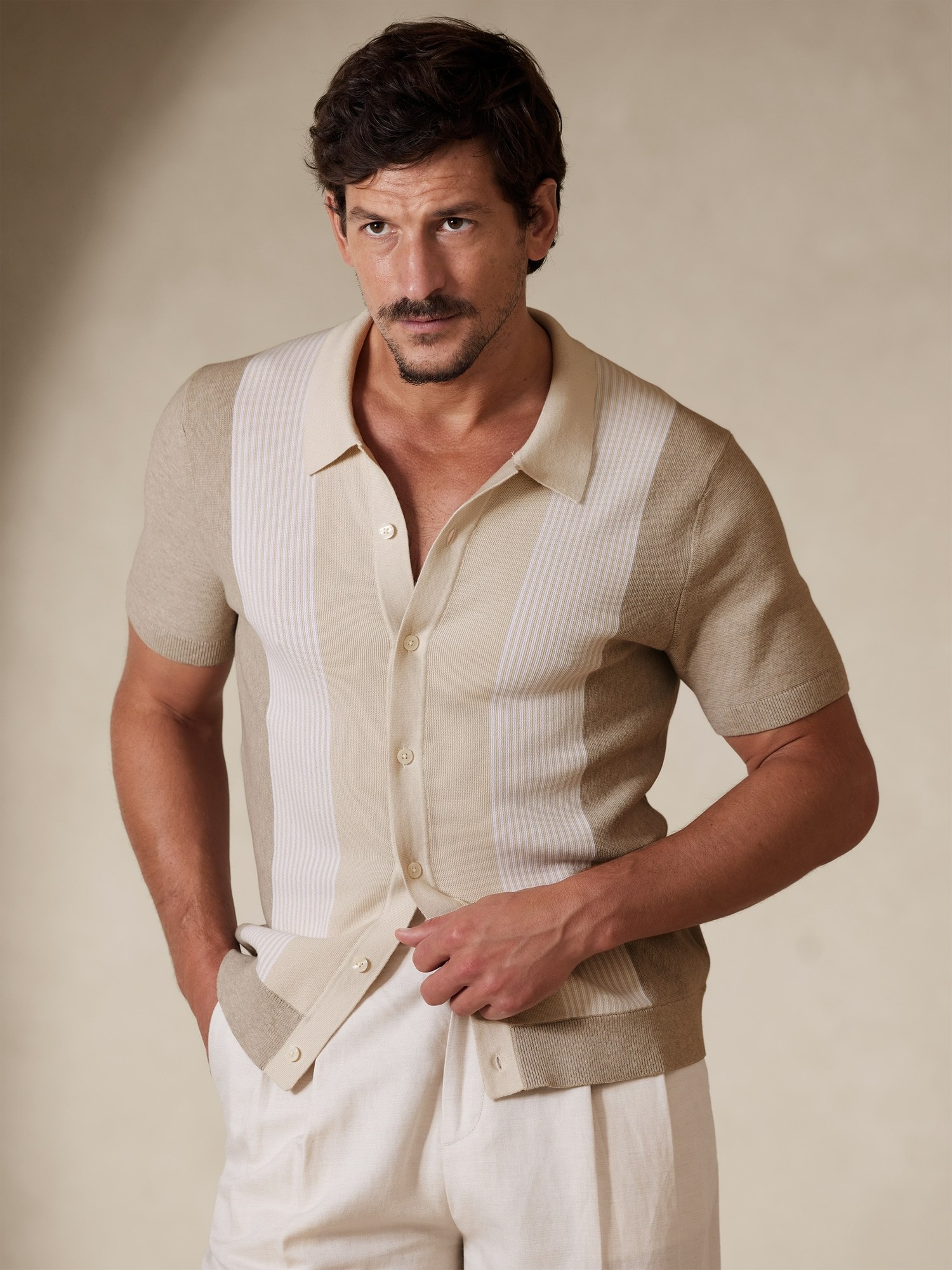 image of a model wearing a beige striped button up short sleeve shirt