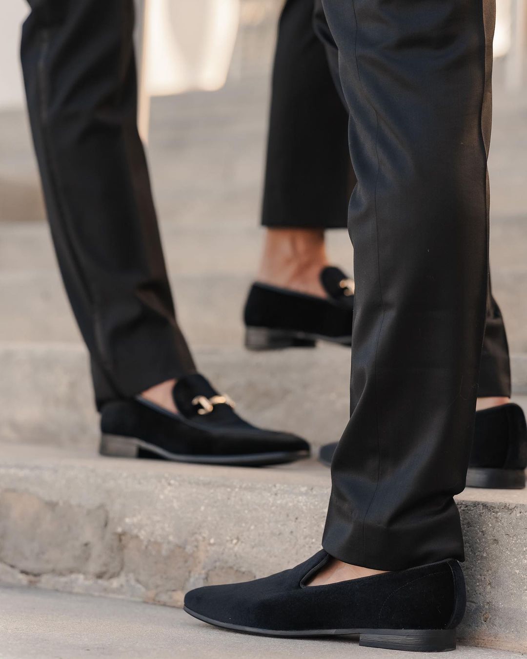 close-up image of two men wearing black loafers