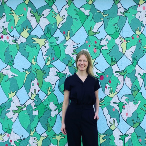 Terese Mullin standing in front of a wall with a pattern of frogs