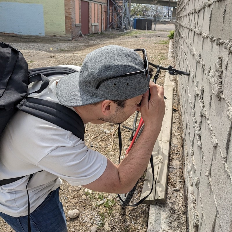 Slavek Pytraczyk with a backpack taking a picture of a wall.