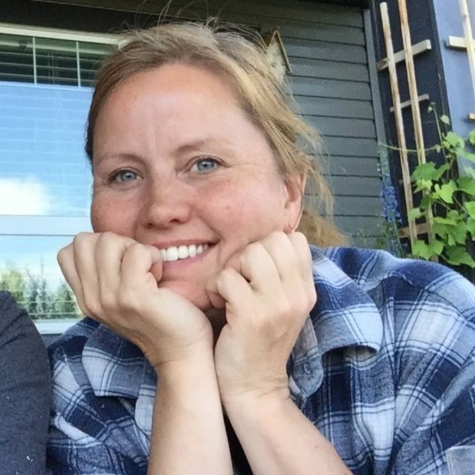 Jennifer Mack smiling with her hands on her chin