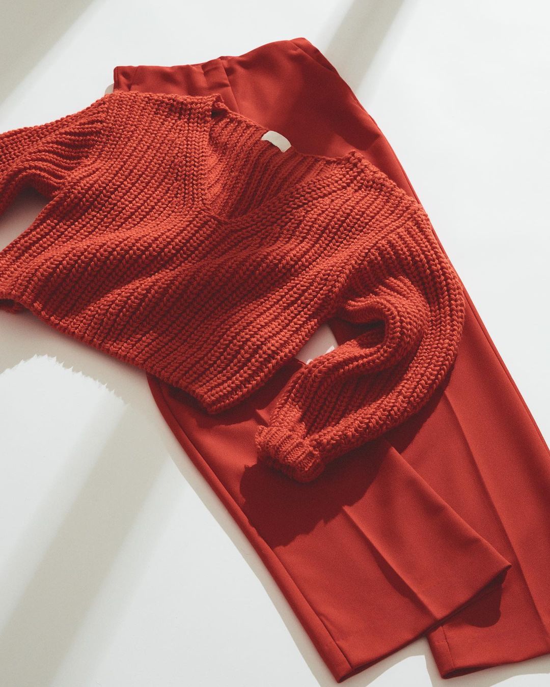 A red sweater and pants laid out on a flat surface.