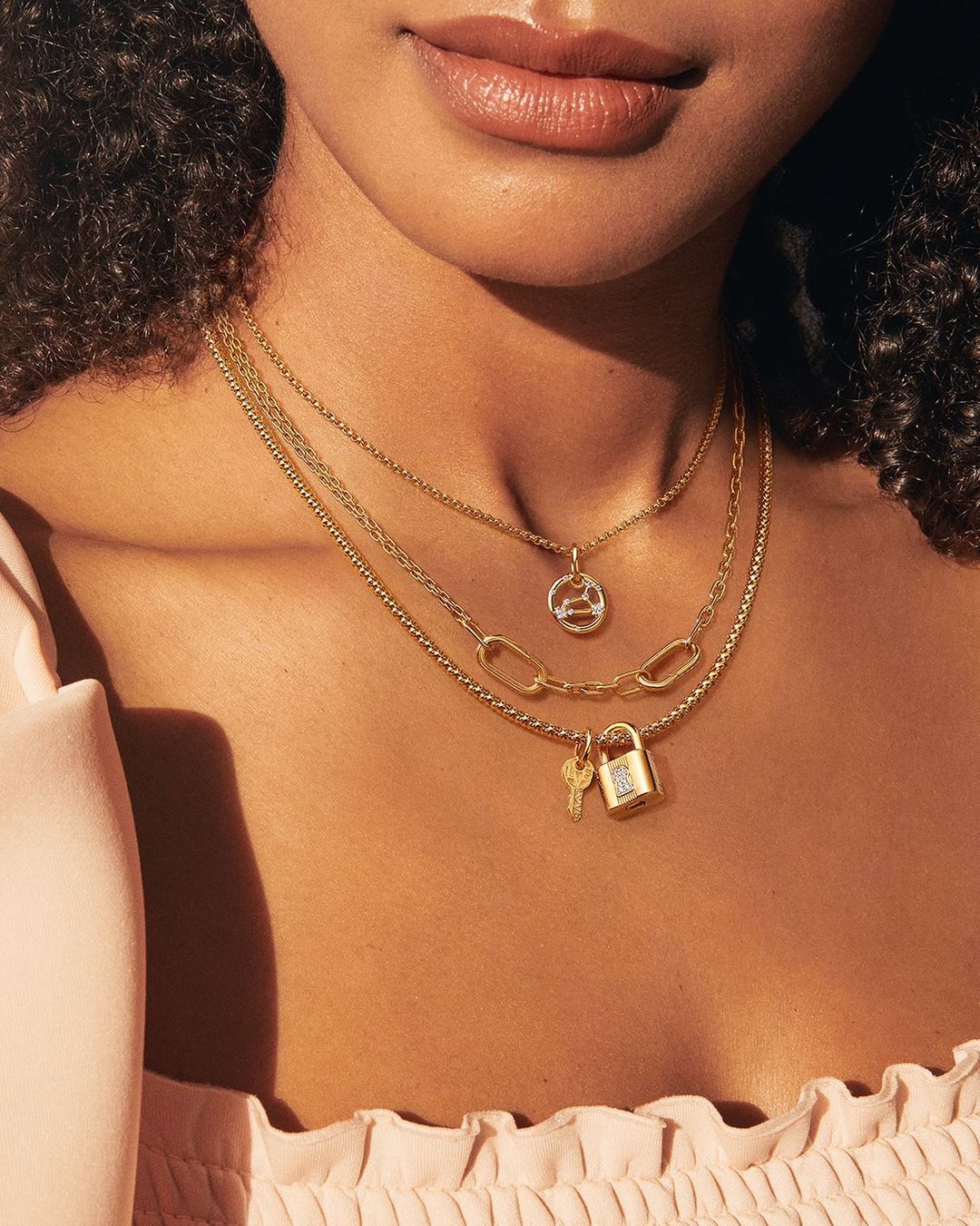 A person wearing multiple stacked gold necklaces.