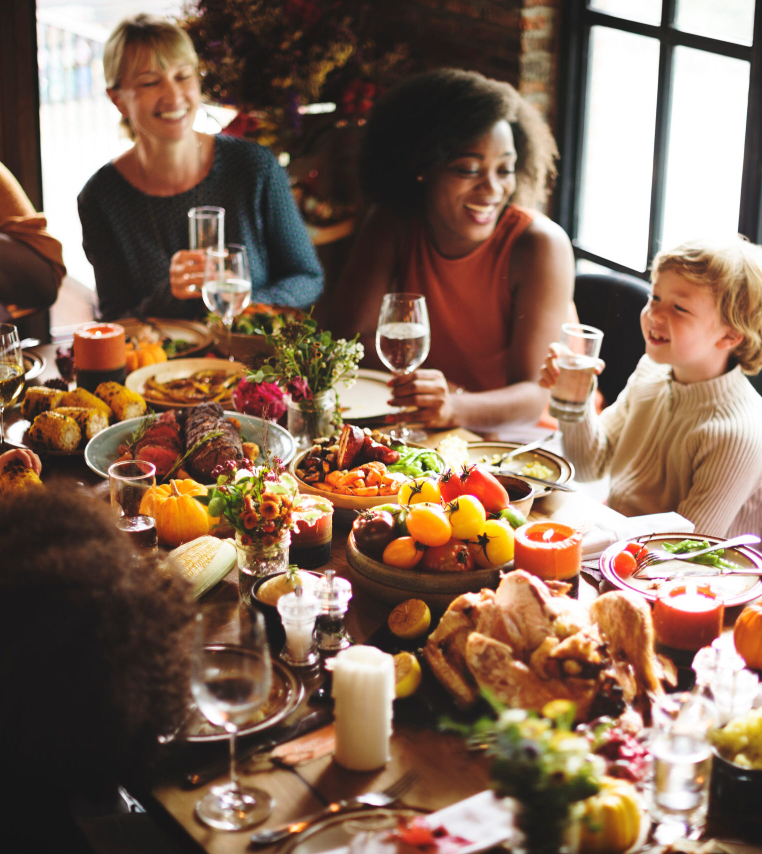 A group of happy people sitting around a table with food and fall decor.