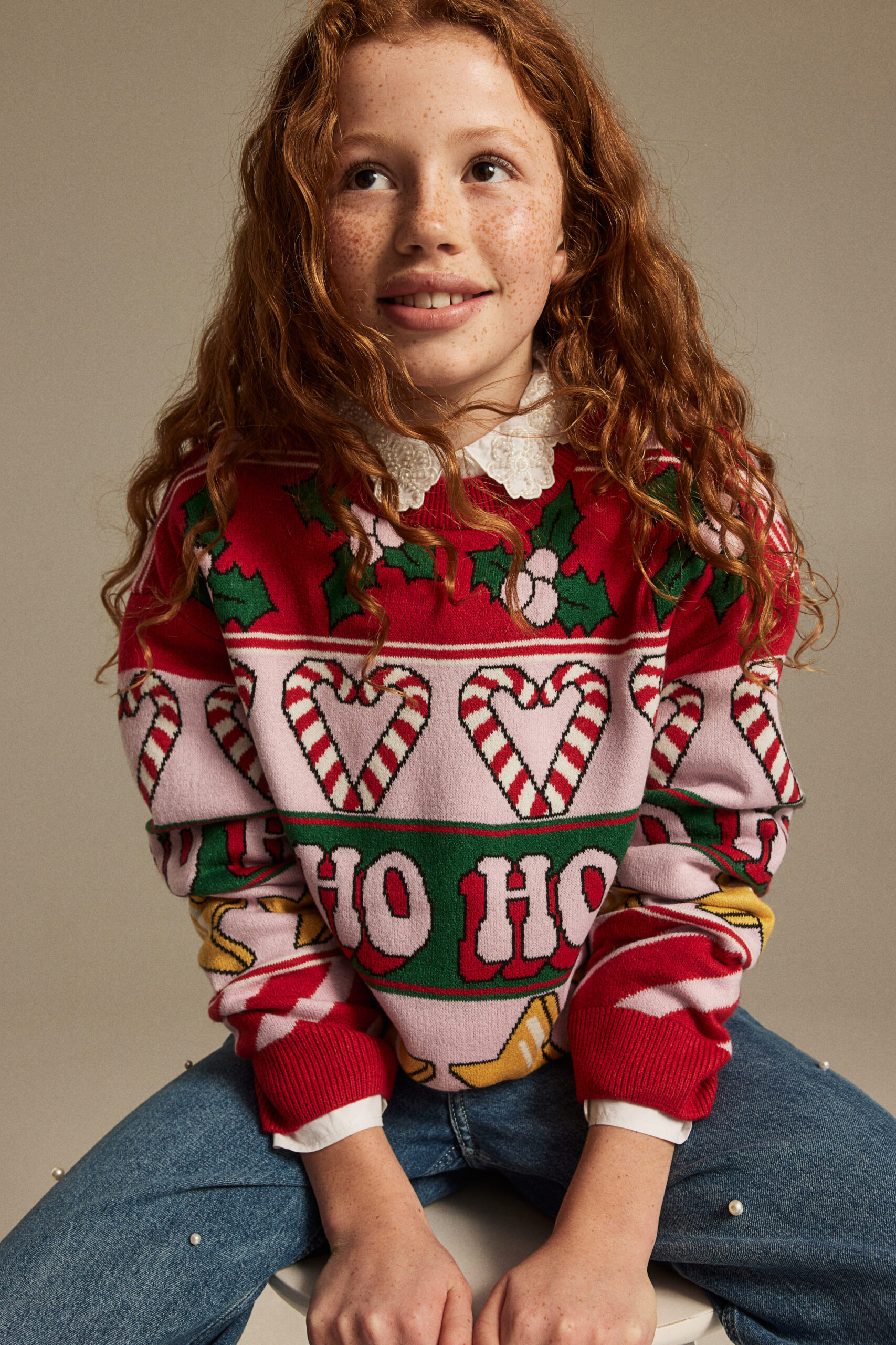 girl wearing knit christmas sweater with candy canes stars and ho ho ho text