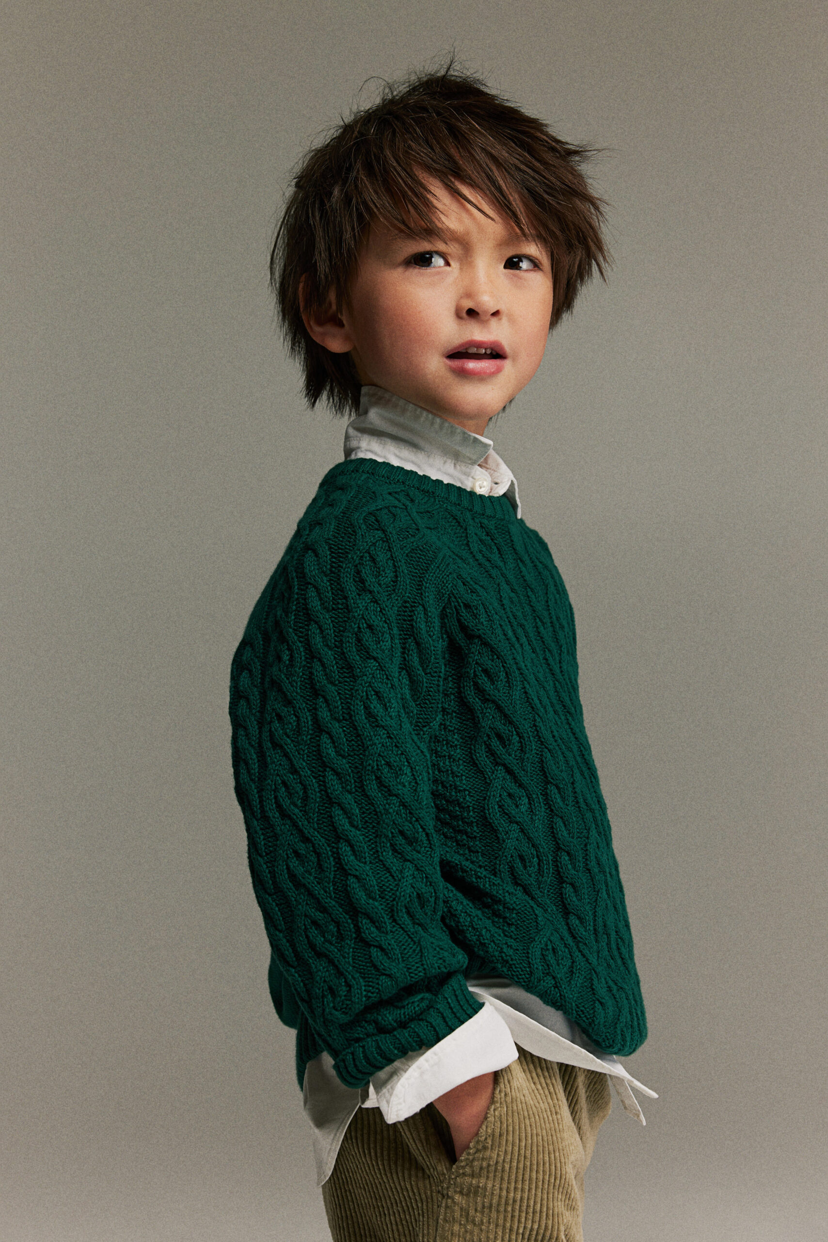 a child in a green cable knit sweater