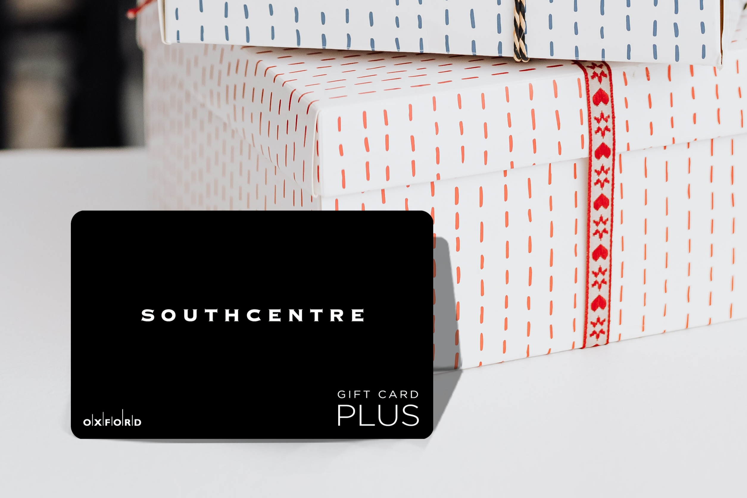 promotional image of a black southcentre gift card in front of gift boxes