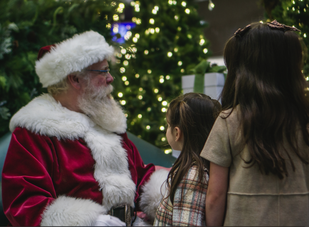 Santa Claus with a child looking at a Christmas tree