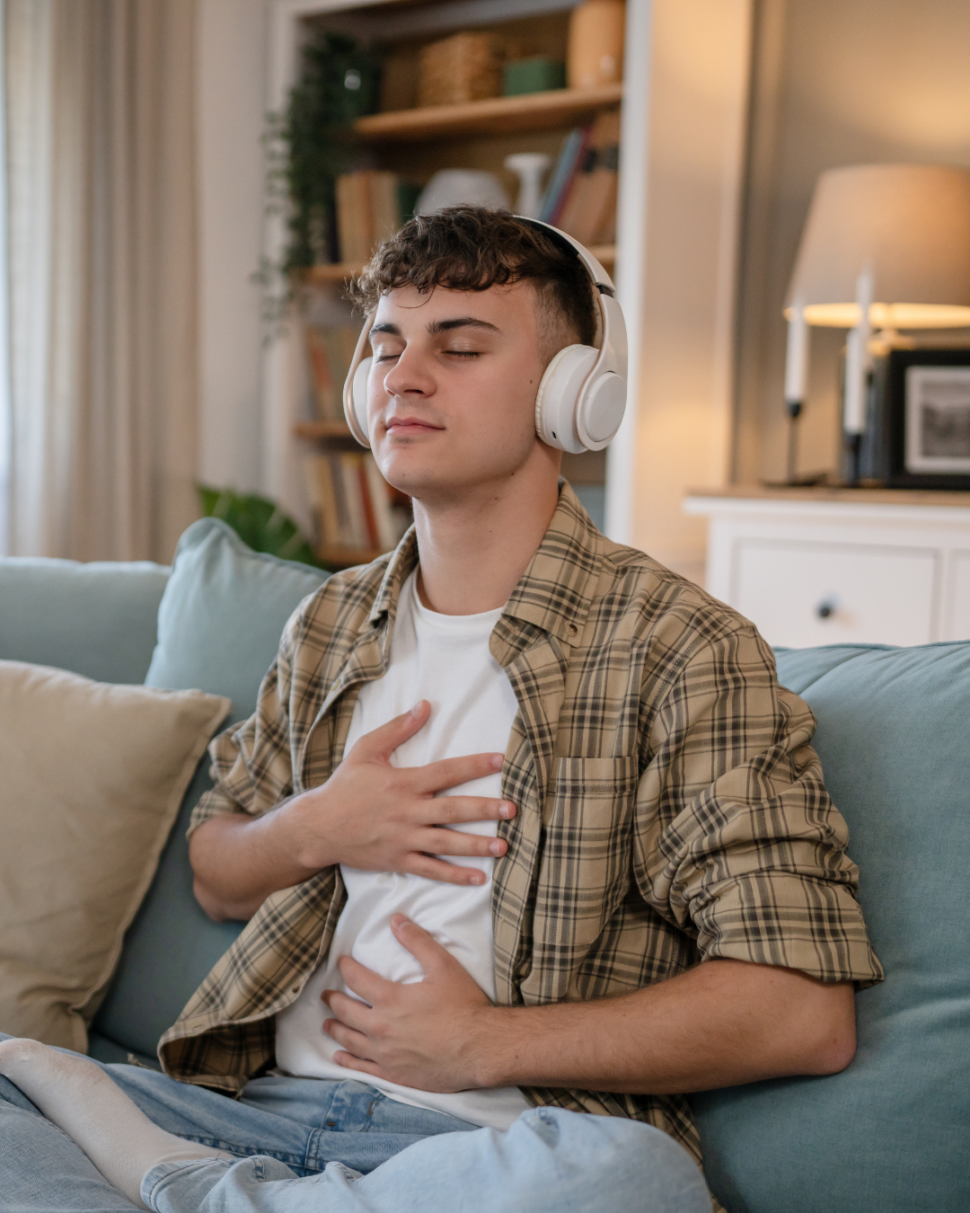 A person wearing headphones and holding his hand on his chest.