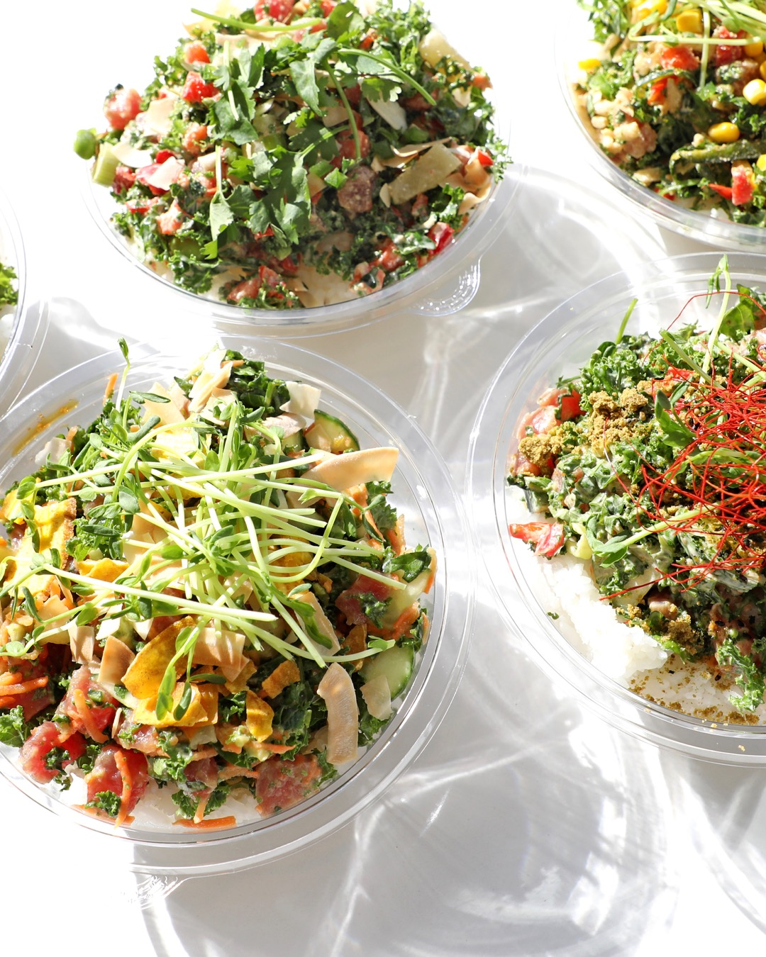 A group of plastic bowls of salad.
