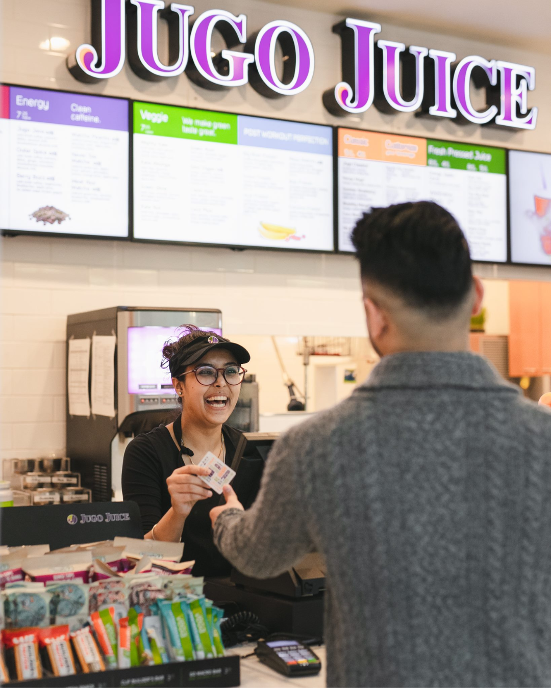 A person smiling at a person at a juice store.