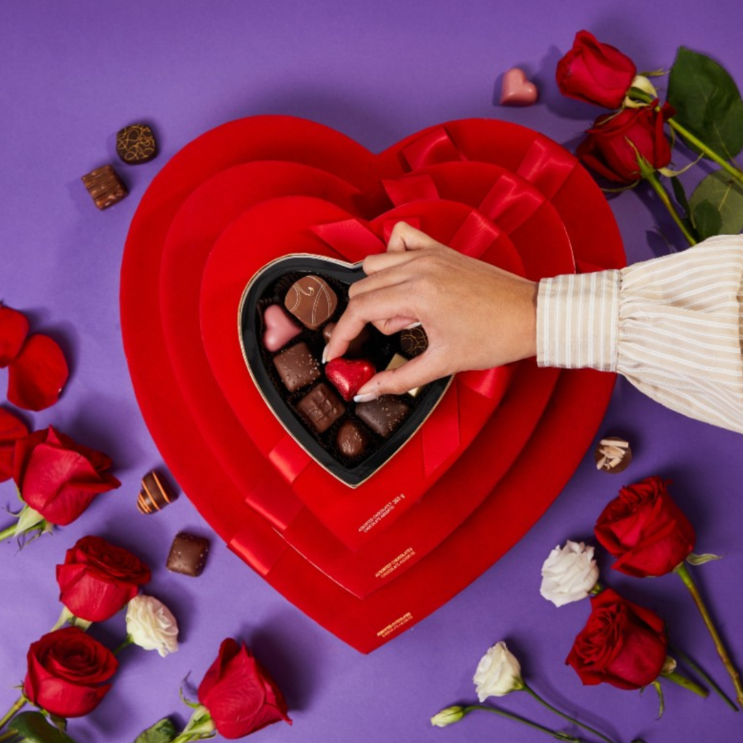 a red heart shaped box with chocolate