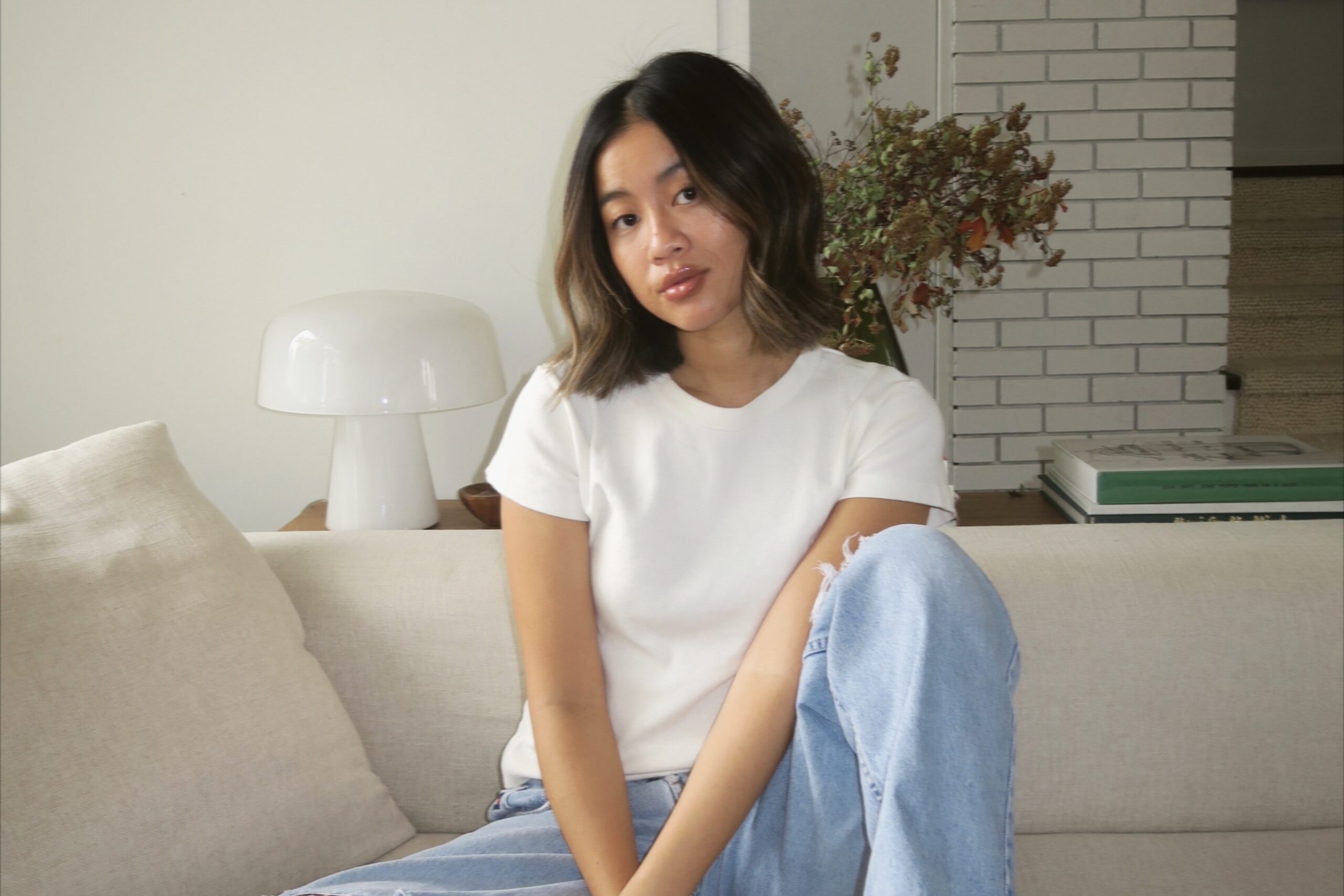 Rachel Spencer Wong sitting on couch with white tshirt and blue jeans