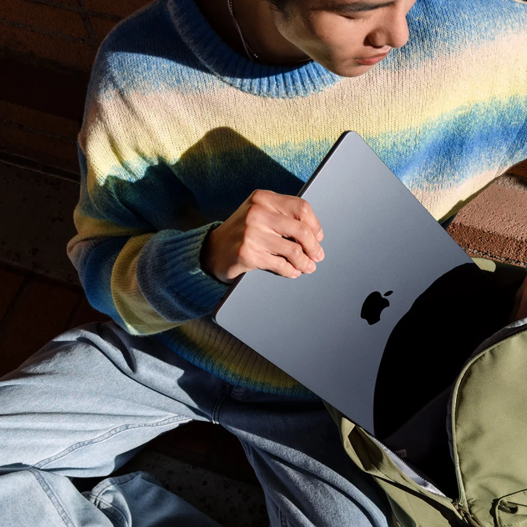 person holding a dark grey Apple MacBook