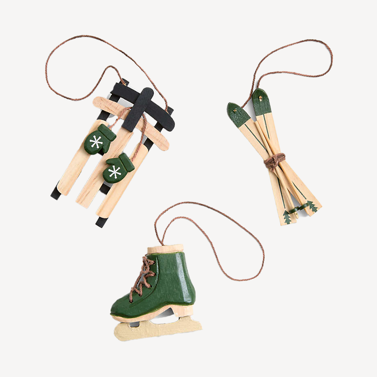 Three green/raw wood Christmas tree ornaments; a sled, a skate, and a pair of skis