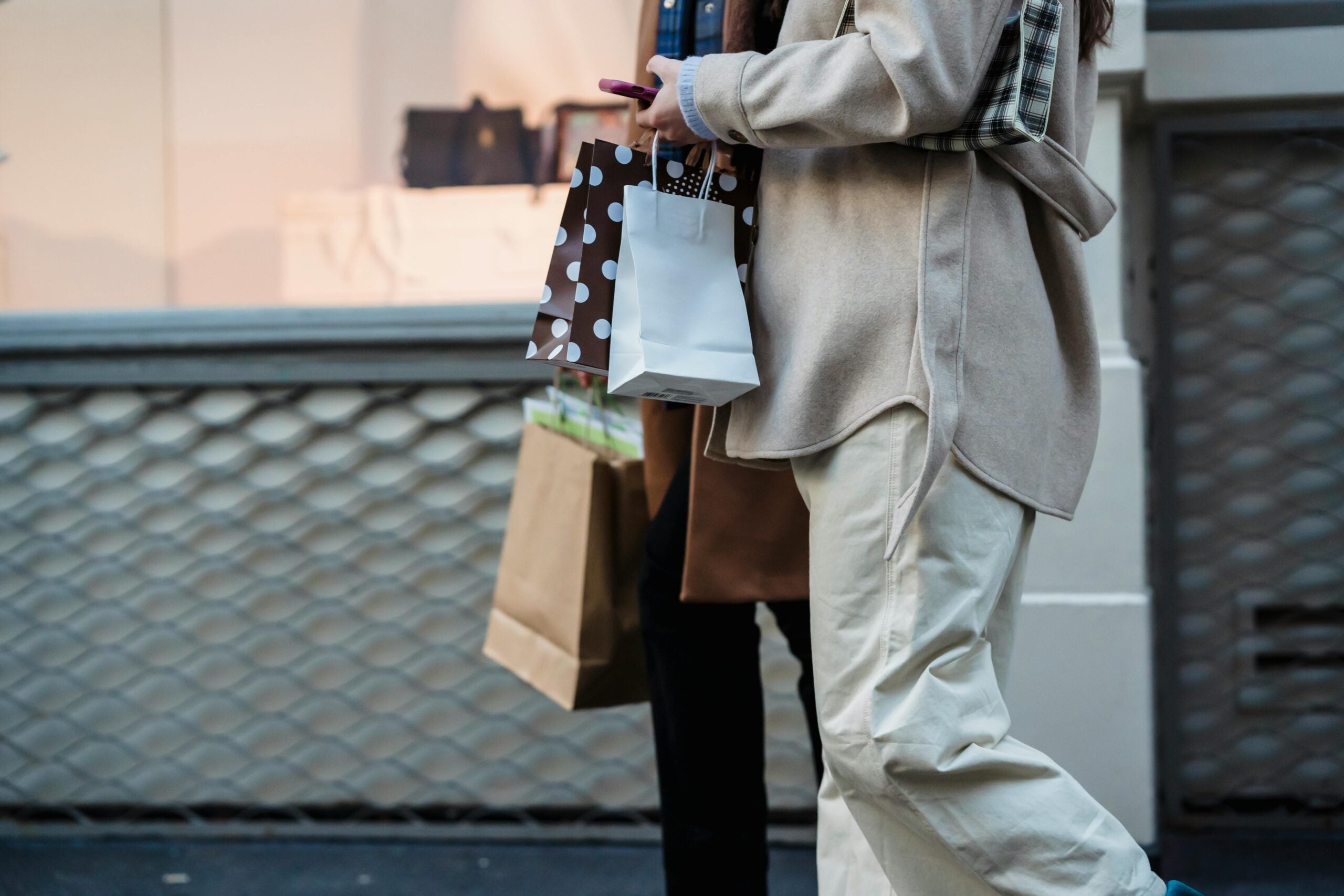 Woman and Man holding shopping bags outside of a store.